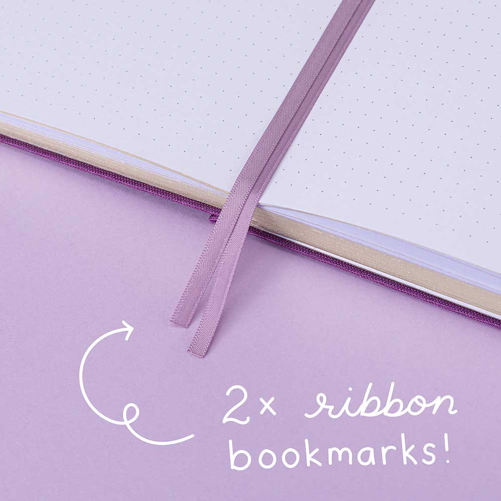 Tsuki ‘Enchanted Garden’ lavender foil design on purple linen bullet journal on purple background with white text saying ‘2x ribbon bookmarks’