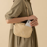 Model in a green dress wearing hinoki travel pouch and putting an iPhone in the pocket