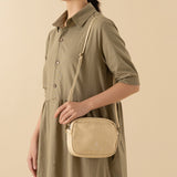 Model wearing a green dress and cream coloured canvas travel pouch