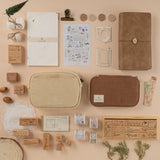 Flatlay of Hinoki products including cream canvas pouch, brown corduroy pencil case, travel notebook, Stamps, washi tape and scrapbook set