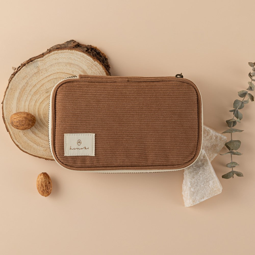 Hinoki Brown corduroy pencil case on wood slice with conker, rocks and eucalyptus as decoration on beige background
