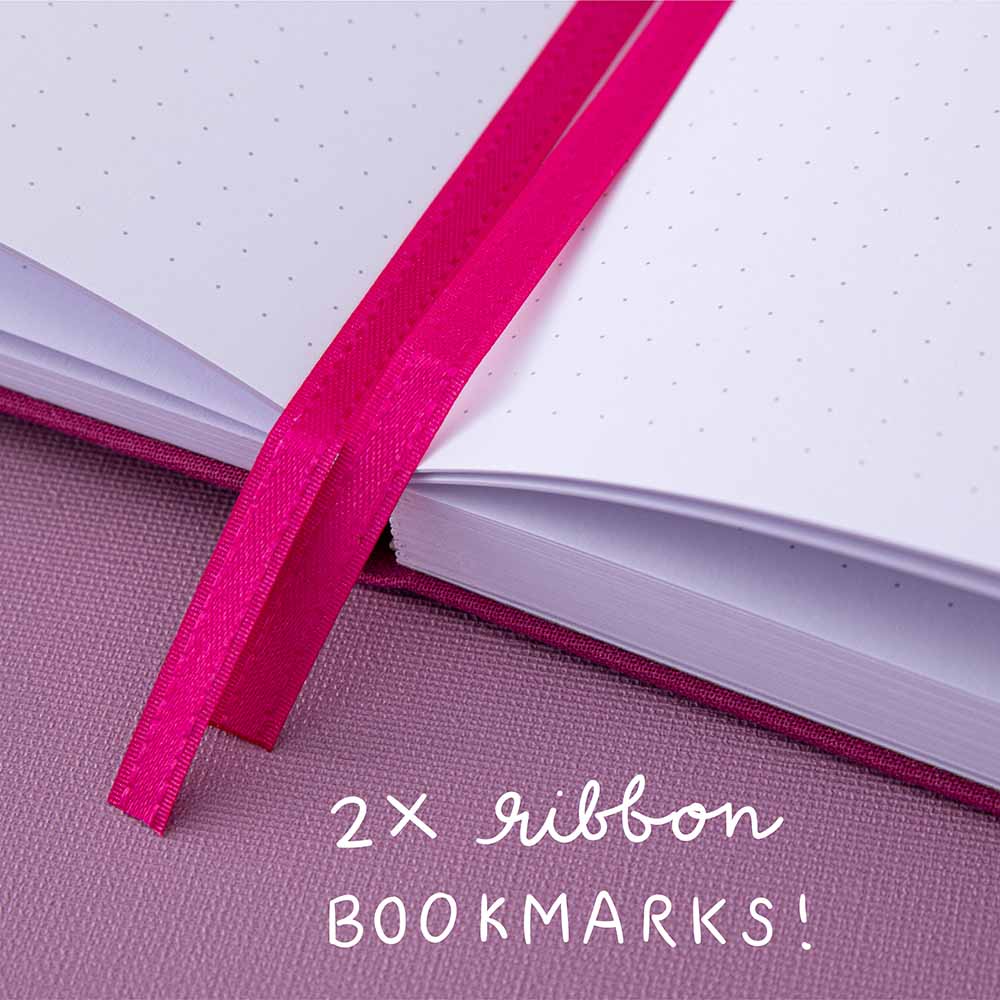 Close up of 2x pink ribbon bookmarks of a bullet journal