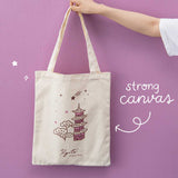 Hand holding a Kyoto tote bag against a pink background with the words “strong canvas” written in white