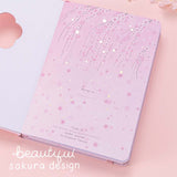 Close up of open front page of Tsuki Four Seasons: Spring Collector’s Edition 2022 Bullet Journal with beautiful sakura design on light pink background