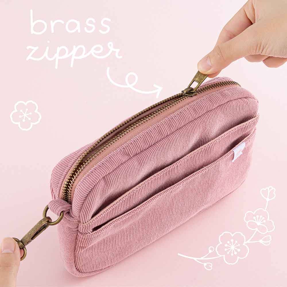 Tsuki ‘Sakura Journey’ Travel Pouch with brass zipper held in hands in pink background