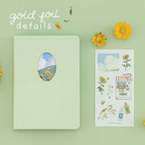 Tsuki Four Seasons Summer Collectors Edition 2022 sage bullet journal notebook on sage background with sunflower decoration and a sticker sheet