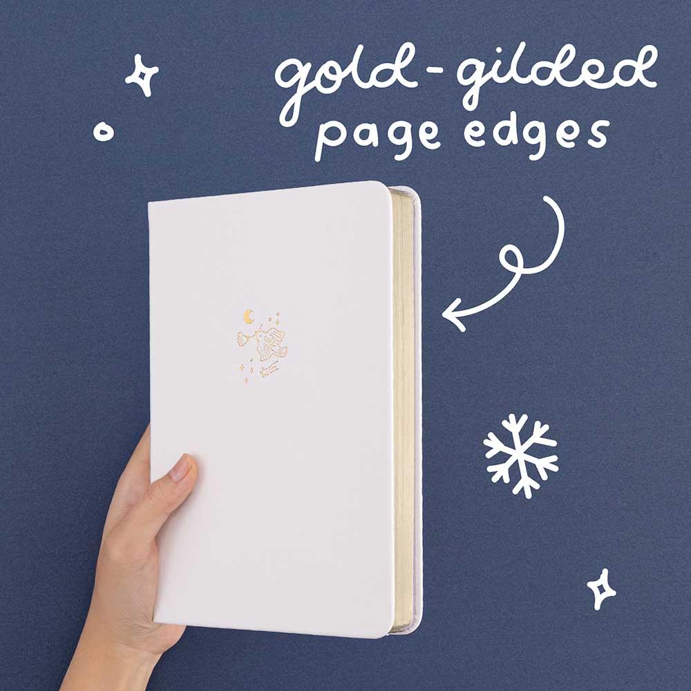 Tsuki ‘Suzume’ Winter Limited Edition Bullet Journal with gold gilded page edges held in hand in navy background