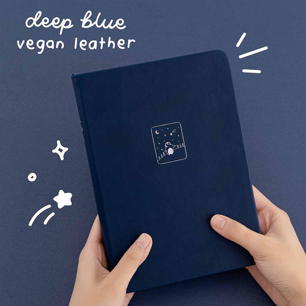 Tsuki ‘Winter Wishes’ Limited Edition Bullet Journal with deep blue vegan leather held in hands in navy background