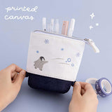 Tsuki ‘Dreams of Snow’ Pop-Up Pencil Case in Playful Penguin with printed canvas held in hands over Tsuki ‘Dreams of Snow’ Holographic Washi Tapes in light blue background